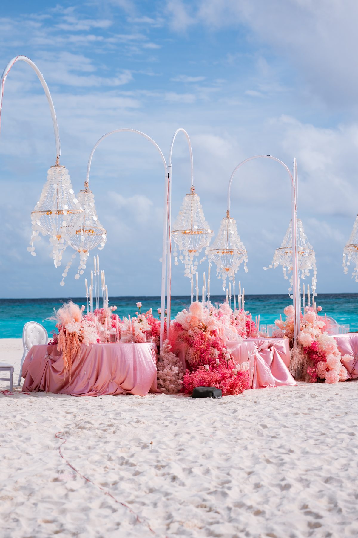 Romantic pink proposal setup on the beach with crystal chandeliers