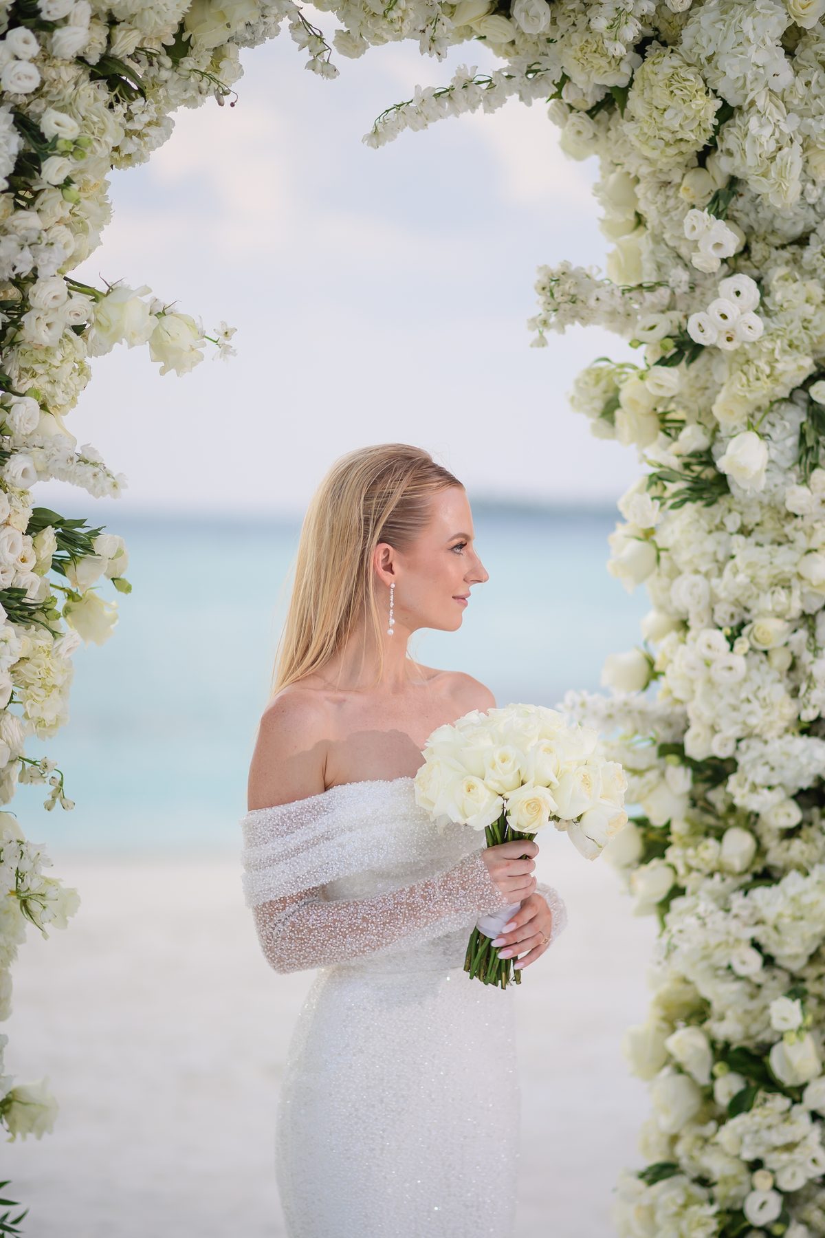 Bride framed by white floral arch at The Ritz-Carlton Maldives